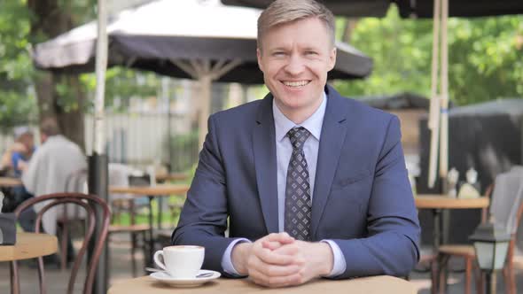 Portrait of Smiling Businessman Sitting in Outdoor Cafe alt
