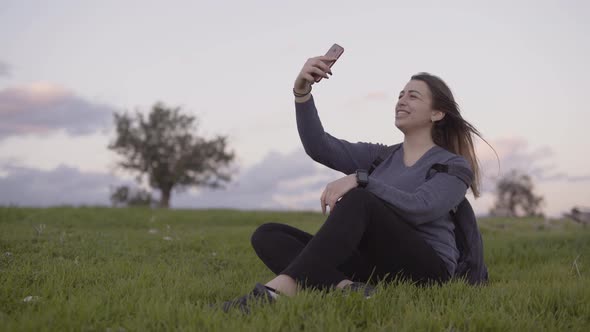 Woman Making Video Call While Sitting in Park in Spring