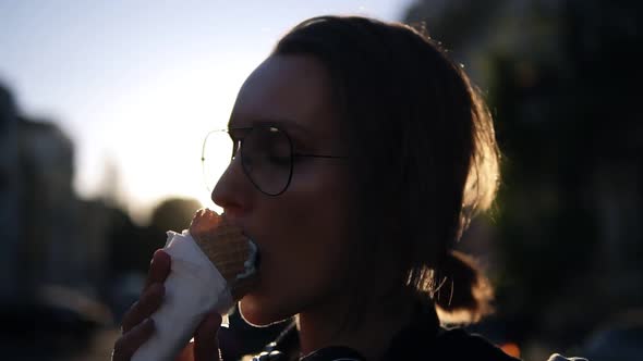 Portrait of a Young Blonde Girl Licking an Icecream in Waffle Cone on the Street alt