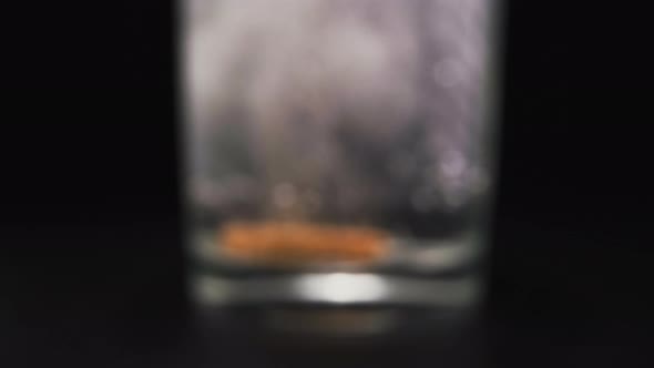 Glass with Falling Down Orange Soluble Tablet and Bubbles alt