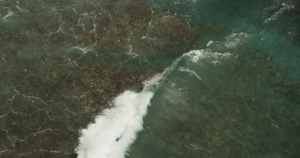 Close Up Slow Motion View of a Shallow Wave Moving on the Water and Crashing Ashore the Rocky alt