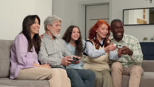 Cheerful Multiethnic Family of Different Age Generations Playing Video Game at Home Sitting on the alt