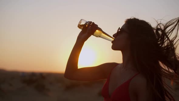 Young Woman Celebrating and Drinking Beer at Beach Party