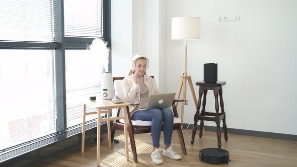 Attractive Female Studying or Working on Laptop While Sitting at Home with Humidifier