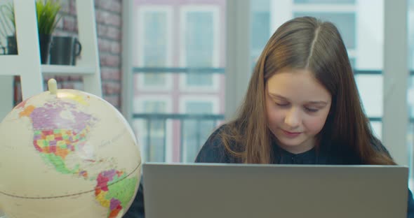 Little Child Girl Using Laptop for Doing School Tasks at Home and Writing Notes alt