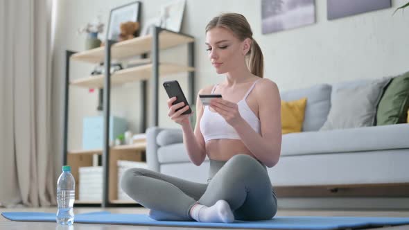 Woman Making Online Payment on Smartphone on Yoga Mat alt