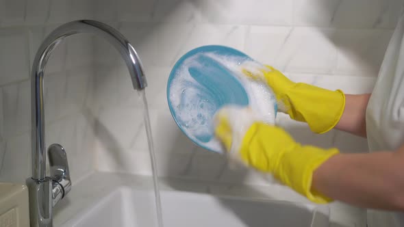 Young Woman in Yellow Rubber Gloves in the Kitchen is Washing Dishes By Hand