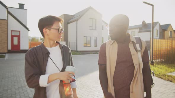 Young Black Man and Asian Woman Walking on Street and Speaking alt