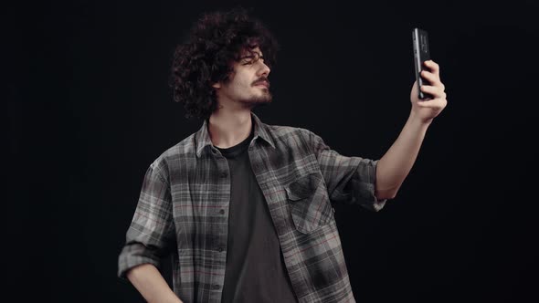 The Focused Young Man Looks at the Phone and Then Receives a Video Call Greets His Caller with His alt