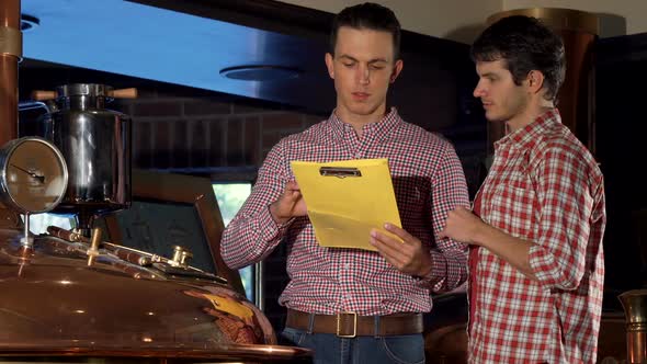 Male Brewer and His Co-worker Examining Brewing Machine at Beer Production alt