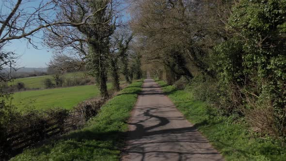 Cotswolds Wooded B-Road On Side Of Vally Zooming Out Aerial Flying Backwards 4K Cine D