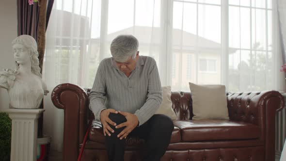 elderly man sitting on couch and massage his knee 