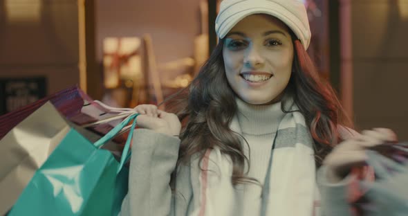 Young woman walking in the city streets and carrying shopping bags, she is happy and shouting