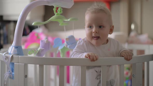 Cute Baby Girl Playing in a Round Crib alt