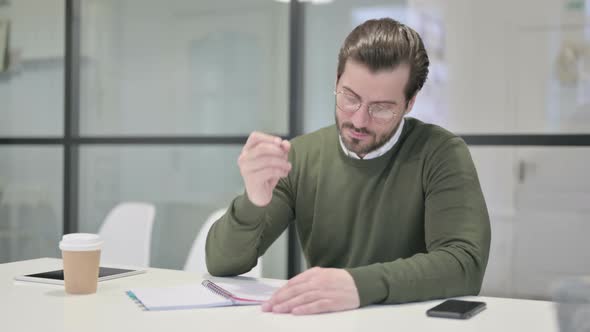 Young Businessman Writing on Paper in Office alt