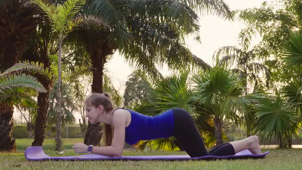 Fitness Woman Doing One Armed Side Plank Exercise on Yoga Mat in Public Park alt