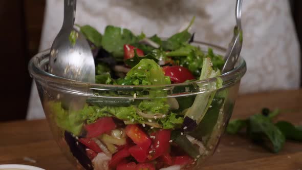 Woman Mixing Fresh Salad in Class Bowl, Close-up.