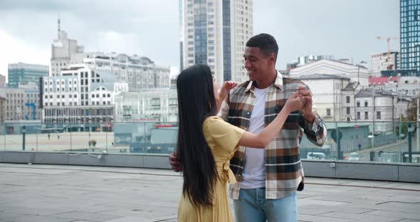 Beautiful Multicultural Loving Couple of Two Cheerful People Dancing at Romantic Date on the Rooftop alt
