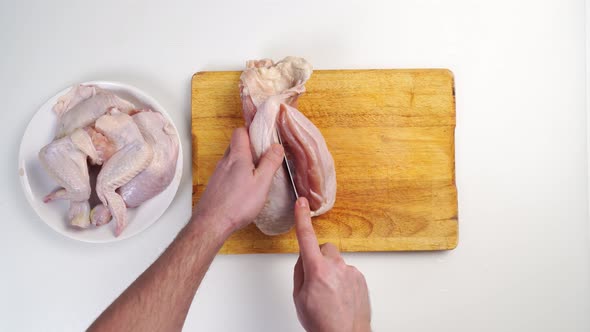 Male Hands Butcher Carcass of Raw Chicken on a Wooden Cutting Board alt