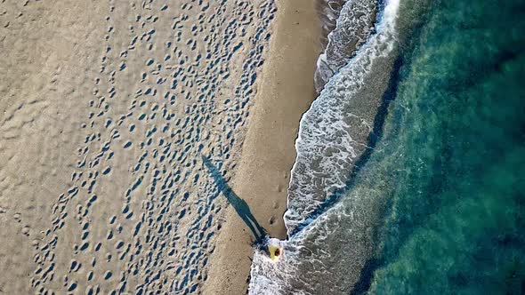 Aerial Drone Footage of a Girl Walking Along a Lonely Beach