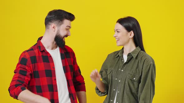 Portrait of a Young Couple Making High Five and Smiling at Camera in Yellow Studio alt