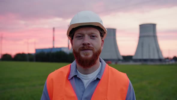 An Engineer in a Helmet and Vest Who Looks Into the Camera with a Smile alt