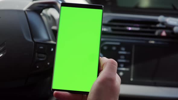 Close Up Hand of the Driver in Car Uses a Smartphone with a Green Screen Inside a Car alt