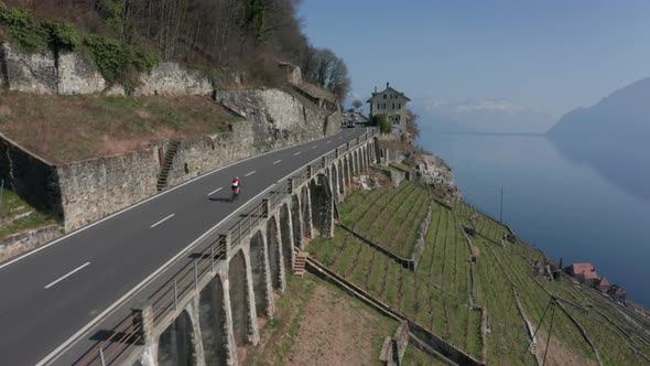Aerial of cyclist cycling uphill over road in countryside alt