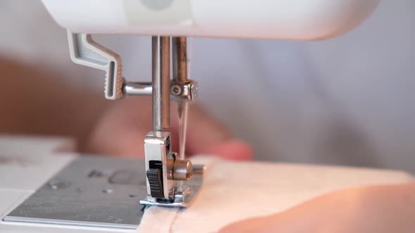 A Woman is Sewing the Hem of Curtains the Edge of a Pillowcase Clothes Sheets on Sewing Machine