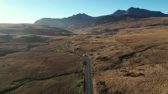 Aerial view of cars on a countryside road through an ample desolate valley in