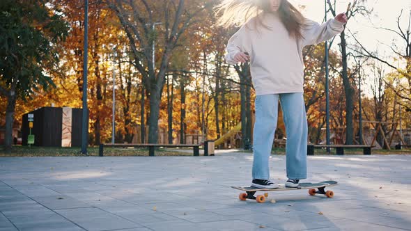 Side View of a Teenage Girl Quickly Rides Along the Sidewalk in Sunny Weather alt