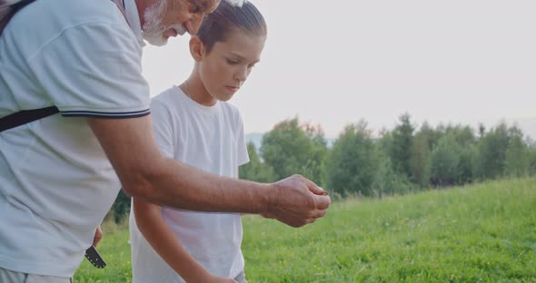 Teenage Boy Carving Wooden Stick with Knife at Campsite alt