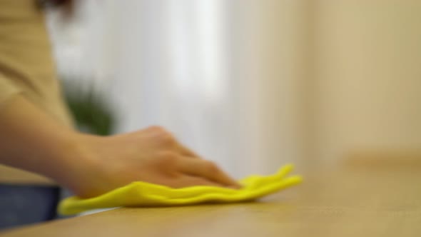 Female Hand Cleaning Kitchen Table with Yellow Disinfecting Wipe