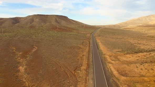 Aerial view of an empty road in dryland of Fuerteventura. alt