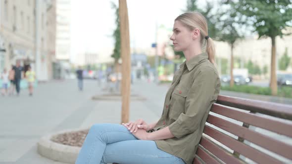 Woman Smiling at Camera while Sitting on Bench alt