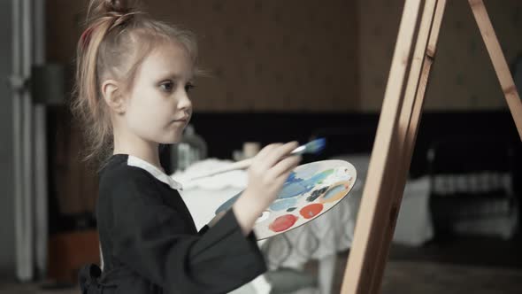 Little Girl With Palette Painting On Easel