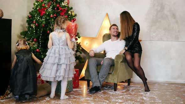 Little Girls Running in the Room and Taking Presents From Underneath the Christmas Tree While Their alt