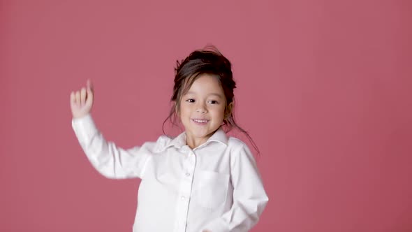 Little Child Girl in White Shirt Dancing on Pink Background.