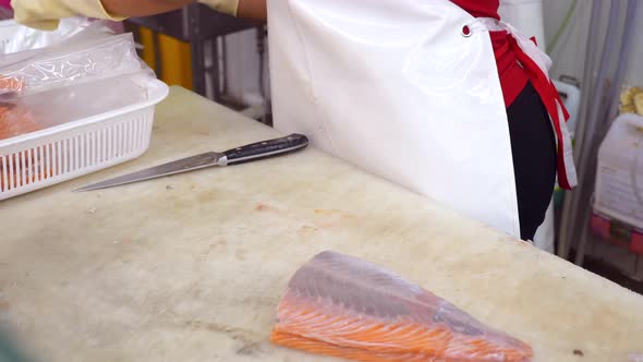 Grocery Store Worker in Gloves Packs Fresh Salmon Fillet In Plastic Portion Bags alt