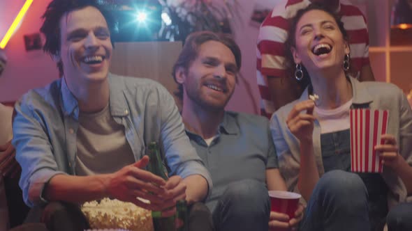 Joyous Friends Watching TV and Laughing while Hanging Out at Home alt