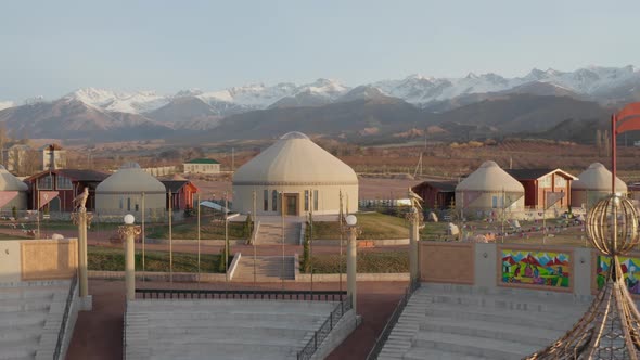 Drone Flight From Height Past the Flags of Dordoi Nomad Amphitheater with Large National Yurts alt