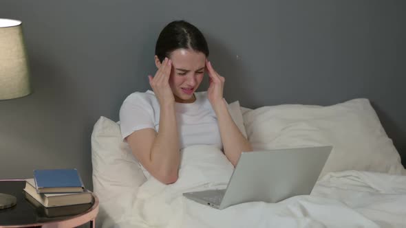 Young Woman with Laptop Having Headache in Bed alt