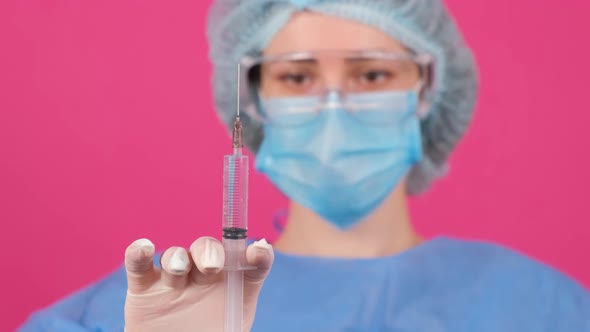 Professional Female Doctor Holds a Syringe with a Vaccine on a Pink Background alt