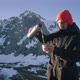 Traveler Pouring Hot Tea From Thermo on Top of Hight Mountain