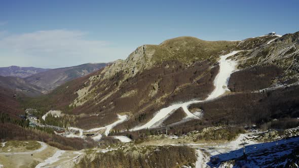 Aerial, Alps Mountains Partially Covered With Snow And Ski Tracks In Italy 