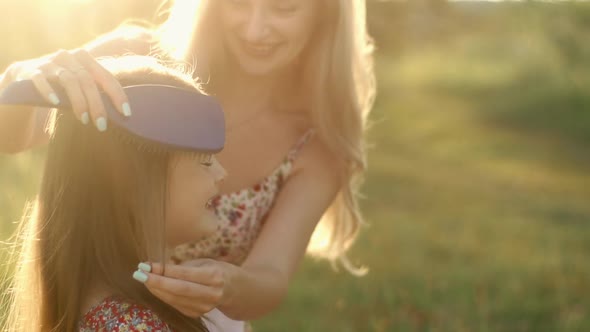 Smiling Blonde Mom in a Summer Dress Combs Her Daughter's Hair