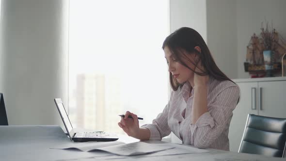 Attractive Girl Working with Documents Drawings Sitting at the Table in the Office alt