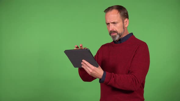 A Middleaged Handsome Caucasian Man Works on a Tablet with a Smile  Green Screen Background