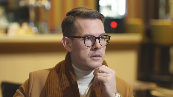 Executive Man in Elegant Coat Sits in Restaurant Concentrated on Thoughts Looking at Side