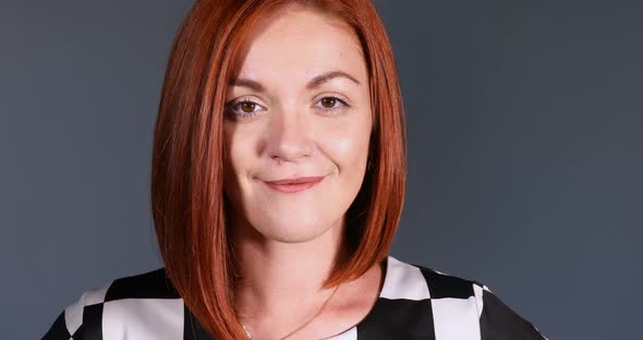 Stylish Red-haired Woman Looking at Camera with Curiosity